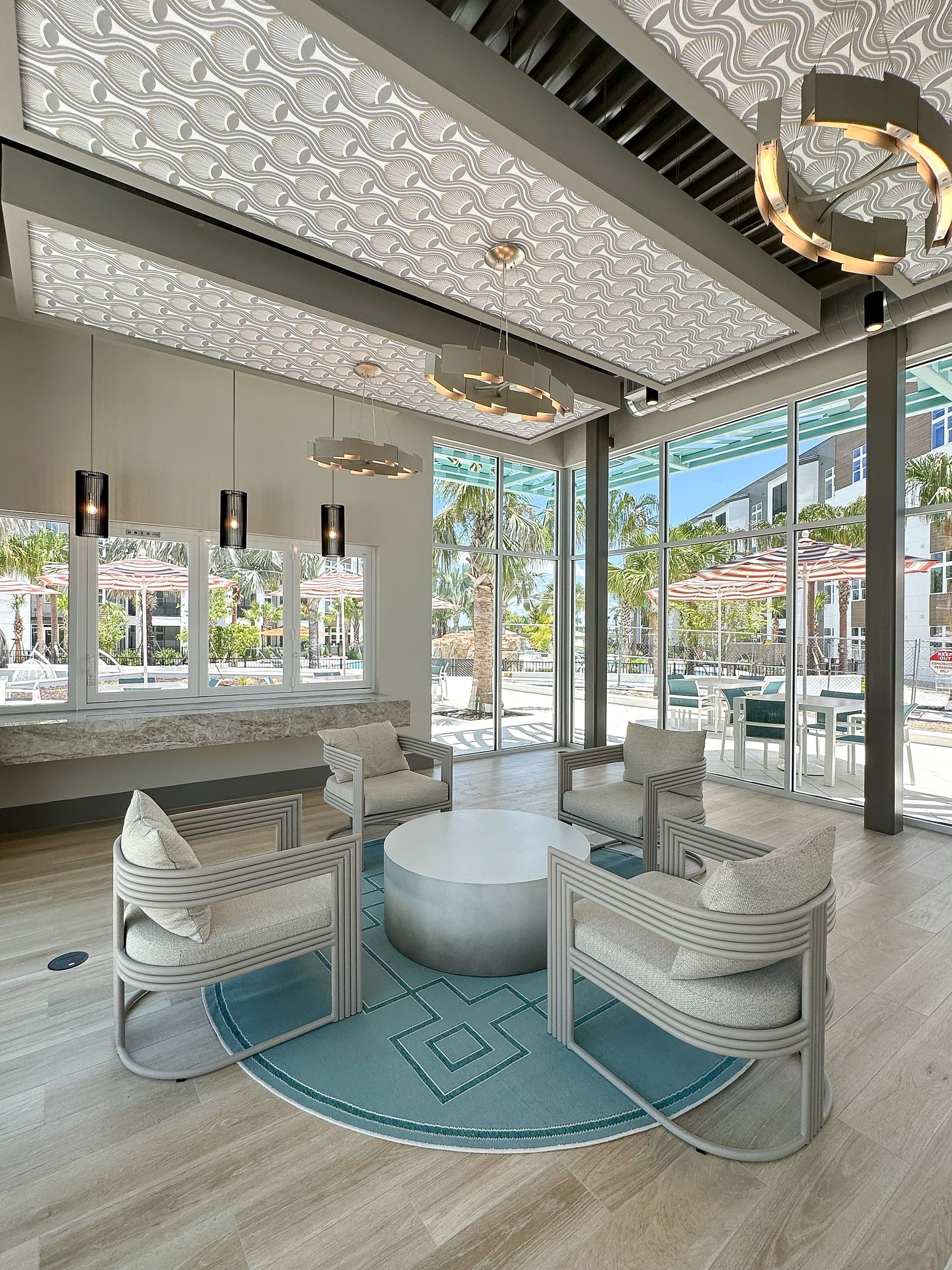 Furnished jewel box with furniture, designer lighting, and floor-to-ceiling windows facing the pool